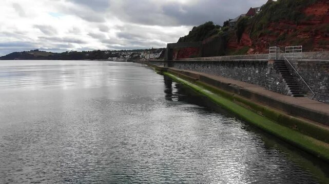 Coastline view showcasing seawall, tranquil waters, and distinctive geography of Dawlish, Devon.