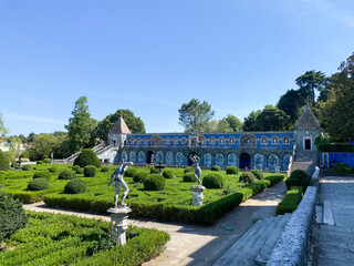Palace garden in Lisbon with ornate blue tiles, lush hedges, sculptures, and classical architecture.