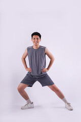 Full body image of Asian guy wearing gym clothes and posing on a white background