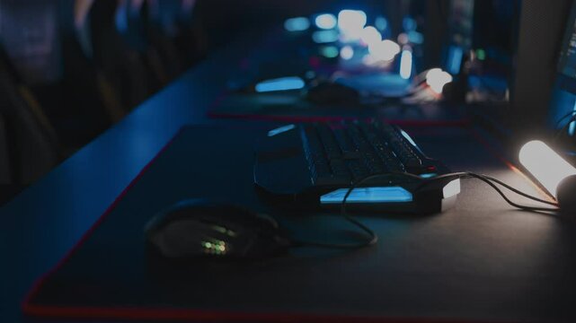 Modern computer club for video games and cyber sport tournament E-sport championship. Gaming mouses and keyboards with RGB lighting animation close up, mat. LAN cafe. No one, nobody. Handheld shot