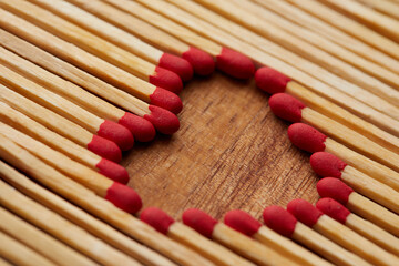 Close-up of heart made of match sticks on wooden background - Love concept