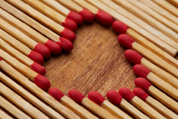 Close-up of heart made of match sticks on wooden background - Love concept