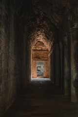 Ancient stone corridor leading to a sunlit entrance.