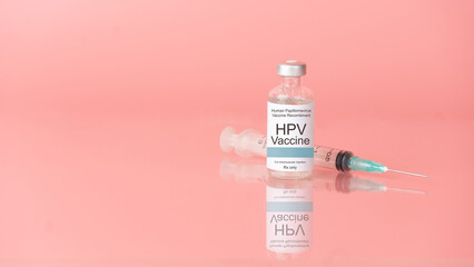 Human papillomavirus (HPV) vaccine bottle with syringe on pink background. HPV vaccine protects...