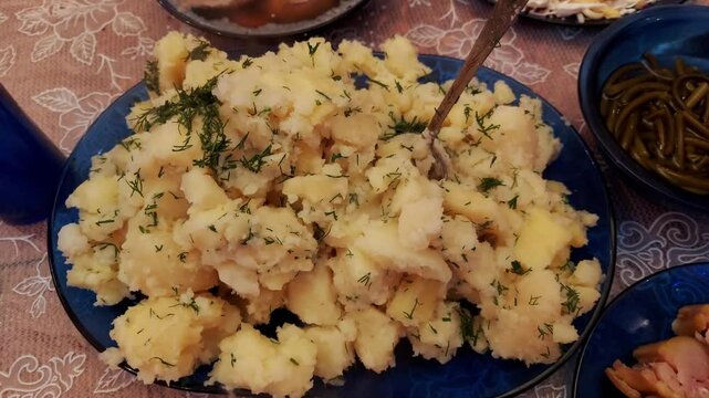 Hot mashed potatoes with dill on a festive home table with dishes and serving, close-up