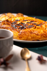 Traditional homemade banana caramel pie. French Tarte Tatin on a white plate with a cup of tea on a green, emerald background. Top view. Close-up.