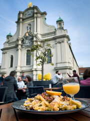 Traditional emperor’s mess  scrambled pancake with views of Holy Spirit Church on background in Munich. European tourism, gastronomy tour concepts