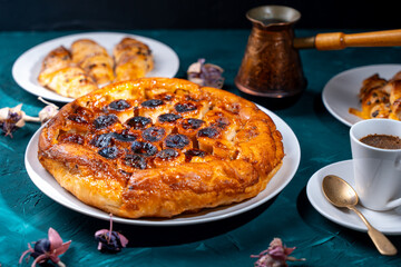 Traditional homemade banana caramel pie. French Tarte Tatin on a white plate with Turkish coffee on a green, emerald background.
