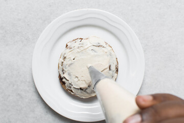 Overhead view of vanilla cookies being frosted, top view of cookies with a vanilla cream frosting, process of frosting cookies