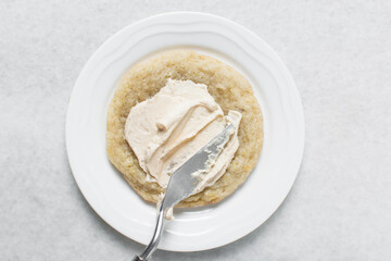 Overhead view of vanilla frosting coated cookies, top view of vanilla cookies with a vanilla cream frosting, process of making bakery style cookies