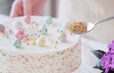 young woman making Easter cake in pastel colors in the kitchen