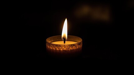 A solitary candle flame illuminates the darkness creating a serene and peaceful glow