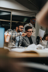 A group of business people working together at night in an office setting. Focused and engaged, they review documents and discuss strategies, signifying teamwork and dedication in a corporate
