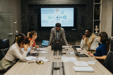 Diverse group of business people focused on a late-night work meeting. They are gathered around a...