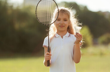 Cute little girl is with badminton racket on the field