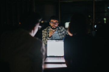 A focused group of coworkers engage in a strategic discussion in a dimly lit room. The professional...