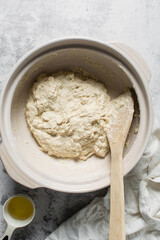 Overhead view of bread dough being mixed in a donabe, top view of homemade bread dough being mixed on granite countertop, process of making artisan bread