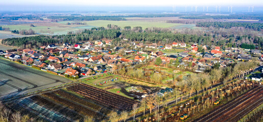 Drone capturing suburban sprawl expanding into countryside with wind turbines