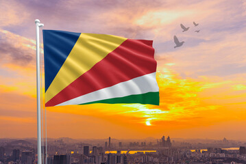 Seychelles flag for Independence and Commemoration Day. Waving flag of Seychelles against the background of a sunset or sunrise. Seychelles sky with flying flag beauty. Concept of national holidays.