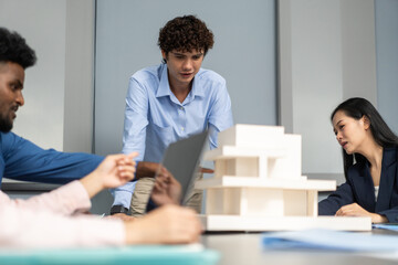 Architects engineers collaborating on building design project in modern office, diverse team of professionals female muslim architect and male engineers discussing architectural model of structure