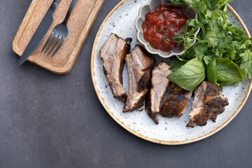 Plate of fried pork ribs with tomato sauce and basil and parsley top view