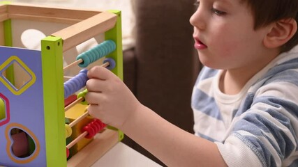 5 year old boy learning to count on colored wooden abacus. Child development and preschool education. kindergarten. Educational games for toddlers. World Autism Awareness Day	