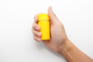 hand holding yellow medicine bottle isolated on white background