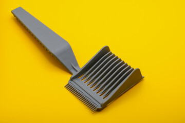 Single lice comb isolated on a yellow surface.  Tool for detecting and eliminating head lice, promoting scalp health and preventing infestations.
