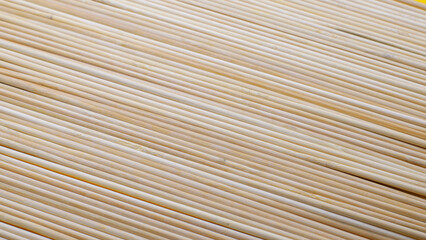 Close-up of a group of wooden toothpicks on a bright yellow surface. Simple, graphic composition with natural, eco-friendly materials.