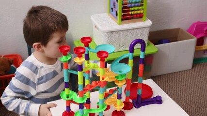 Boy playing in a ball maze, graviton constructor. Concentration and perseverance in children, development of logic and intelligence. world autism day - Powered by Adobe