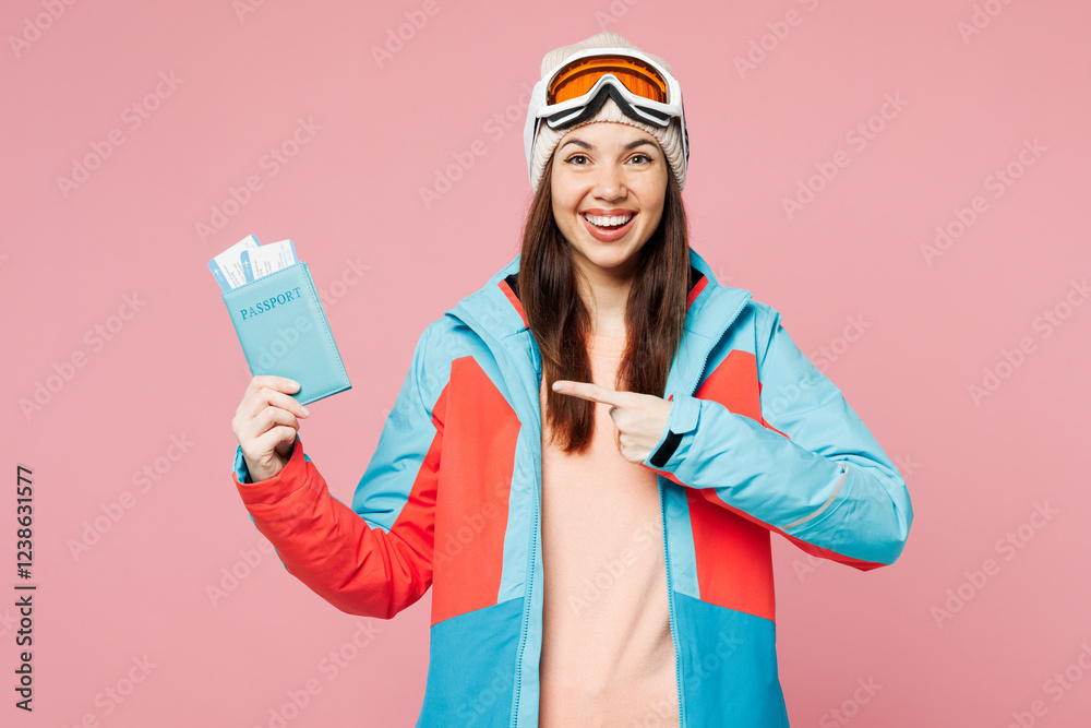 Poster Traveler woman wear blue padded jacket ski goggles mask hold point on passport ticket isolated on plain pink background Tourist travel abroad in free time rest getaway Air flight trip journey concept