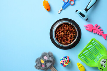 Cat care essentials on a blue background, including food bowl with kibble, grooming tools, toys,...