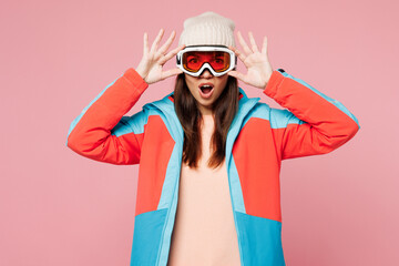 Snowboarder shocked surprised amazed young woman wear warm blue padded jacket put on ski goggles mask spend extreme weekend winter season in mountains isolated on plain pink background. Hobby concept. © ViDi Studio