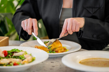 A close-up of a person using a fork and knife to cut into a delicious omelette on a plate. Fresh salads and a bowl of soup are visible in the background, highlighting a cozy dining experience.