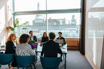 Group of male and female business professionals discussing during meeting in board room at office