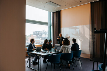 Female business professional brainstorming colleagues in team meeting at office