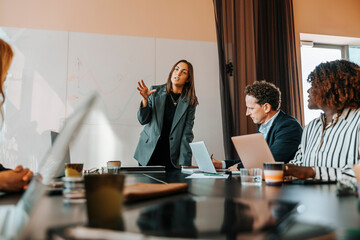 Businesswoman discussing strategies with colleagues sitting on board room