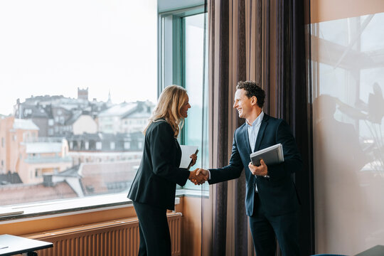 Happy male and female business professionals doing handshake at office