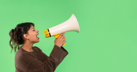 Woman shouting into megaphone against bright green background during an energetic moment