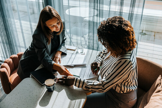 High angle view of female entrepreneur helping client while filling form