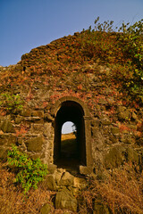 Ruins of Korlai fort depicting an arched gateway through  the ancient stone wall. Korlai fort is a Portugues colonial naval fort situated in Raigad district of Maharashtra, India.