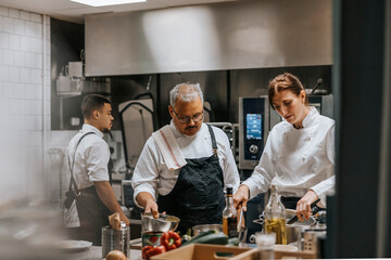 Female and male chef wearing uniform cooking food in kitchen at restaurant