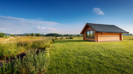 Obraz premium Small Wooden Log Cabin in Rural Landscape Stock Photo