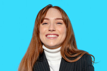Smiling woman with long hair in stylish outfit against a bright blue background