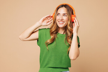 Young smiling happy woman wear green t-shirt casual clothes listen to music in headphones look...