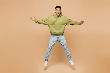 Full body young shocked surprised man of African American ethnicity wearing green hoodie casual...