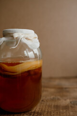 Fresh kombucha in a glass jar on a wooden background. Space for text