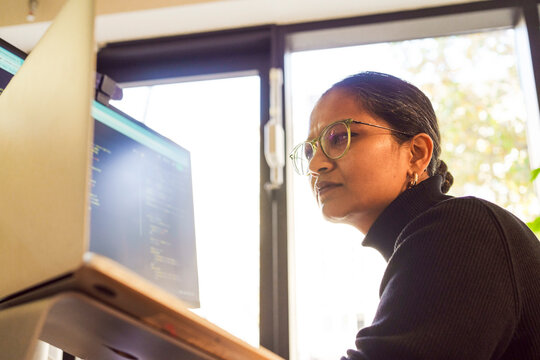 Low angle view of confused female programmer using laptop in office