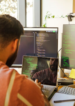 Male IT professional coding on laptop in tech startup office