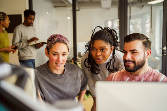 Multiracial male and female computer programmers discussing with each other in tech office
